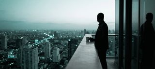 A silhouette of a man looking at a city skyline.